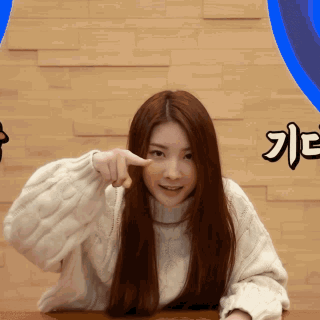 a woman wearing a white sweater is pointing her finger at something