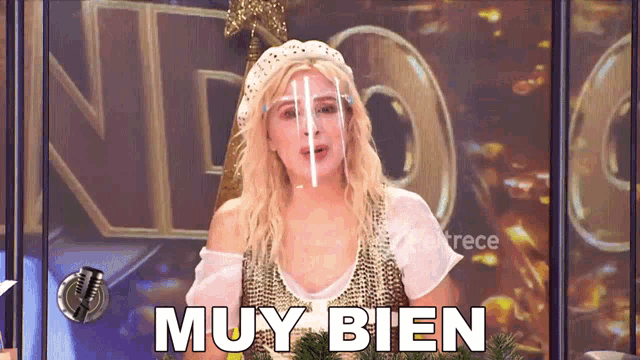 a woman wearing a face mask says muy bien in front of a microphone