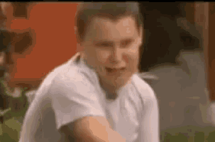 a young man in a white shirt is crying while sitting down .