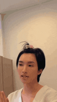 a man with his hair in a bun is talking to someone .
