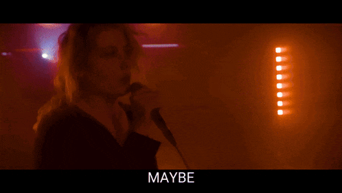 a woman singing into a microphone with the word strange written below her