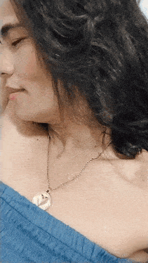 a woman wearing a blue off the shoulder top and a gold chain necklace