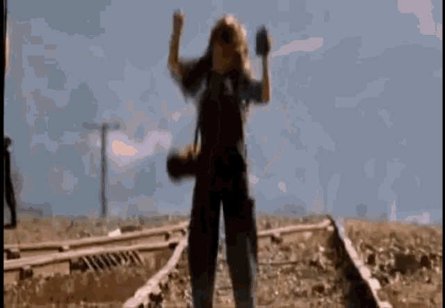a person is standing on train tracks holding a cell phone