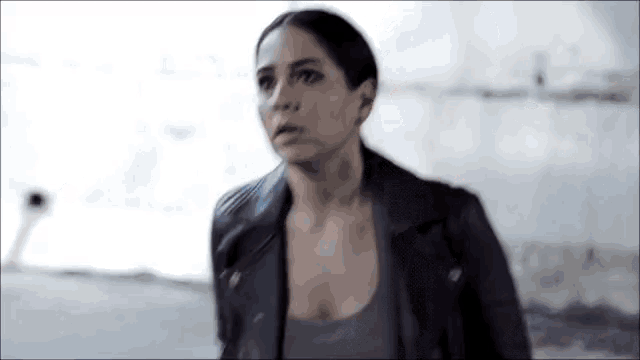 a woman in a black leather jacket is looking at something