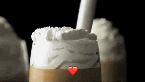 a cup of coffee with whipped cream and a red heart