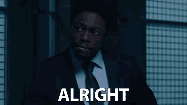 a man in a suit and tie says alright in white letters