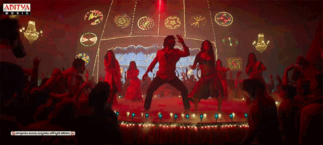 a group of people are dancing in front of a sign that says ' aditya music ' on it