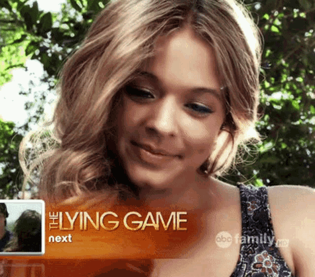 a woman is smiling in front of an ad for lying game next