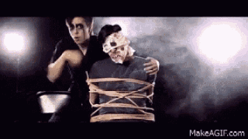 a man is holding a woman tied up with ropes .