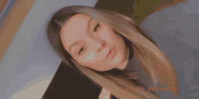 a close up of a woman taking a selfie with her hand in her hair .