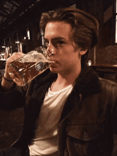 a young man is drinking from a glass that says heineken