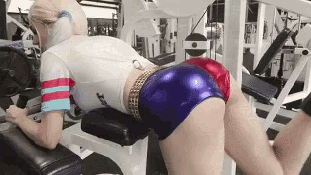 a woman in a harley quinn costume is doing leg exercises in a gym
