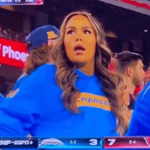 a woman wearing a blue charge sweatshirt looks surprised