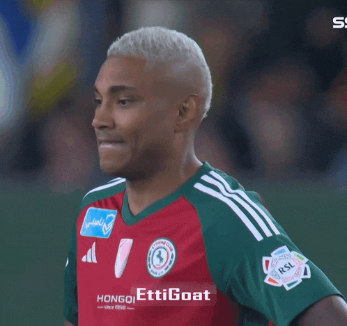 a soccer player wearing a red and green jersey that says ettigoat on it