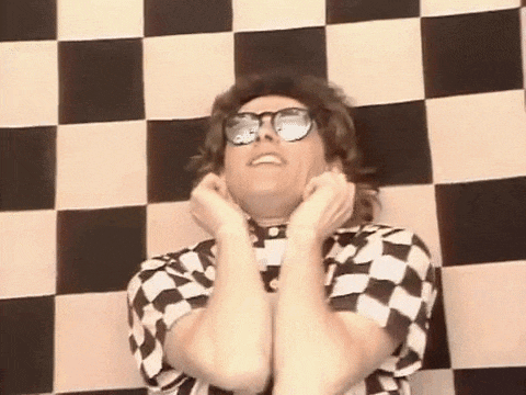 a man wearing sunglasses and a checkered shirt is covering his ears .
