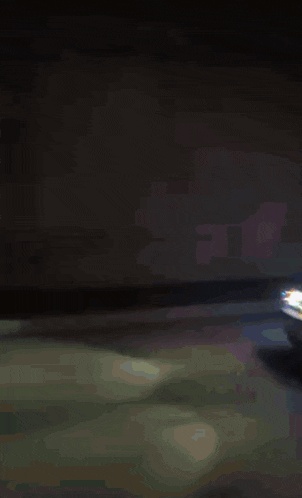 a car is driving down a street at night with a lot of lights behind it