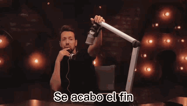 a man sitting in front of a microphone with the words se acabo el fin written below him