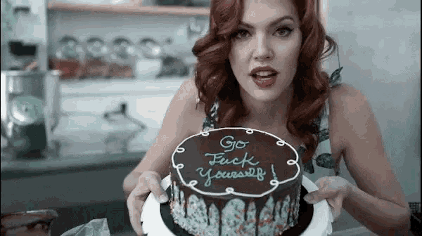 a woman holding a cake that says go fuck yourself on it