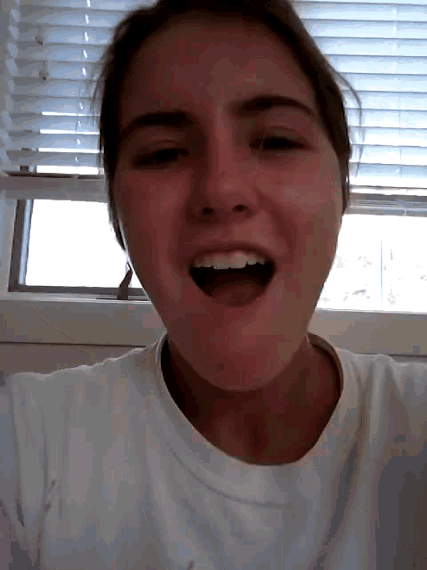 a woman with her mouth open is wearing a white shirt