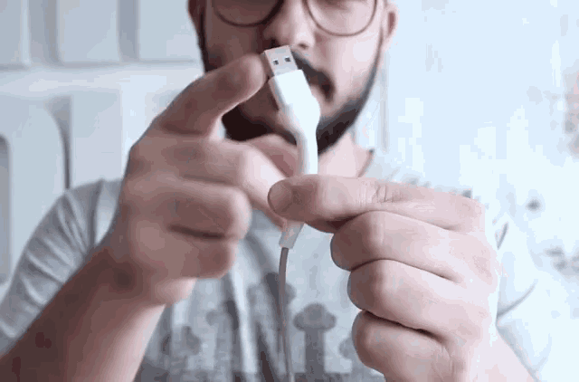 a man with glasses holds a usb cable in his hand