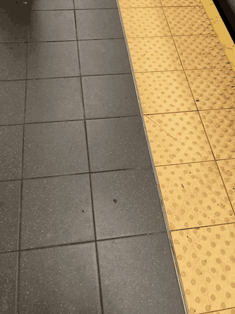 a black tile floor next to a yellow tile border