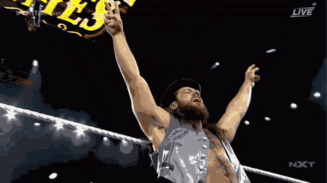 a man in a wrestling ring with his arms in the air and a sign in the background that says live