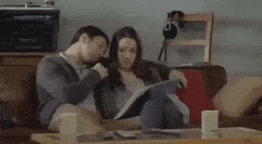a man and a woman are sitting on a couch in a living room .