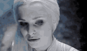 a close up of a woman 's face with white hair and a blue background .