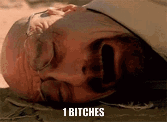 a close up of a man laying on the ground with the words 1 bitches above him