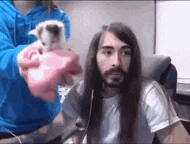 a man with long hair is sitting in front of a woman holding a small kitten .