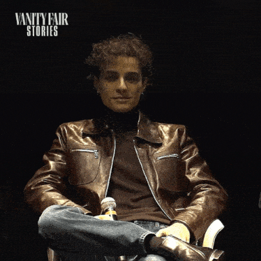 a man in a brown leather jacket is holding a brush in front of a vanity fair story