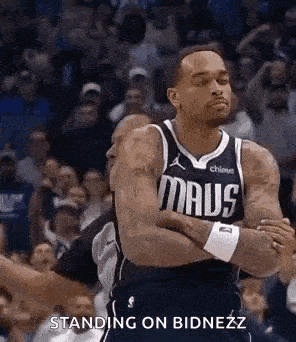 a basketball player is standing on the court with his arms crossed and a crowd behind him .