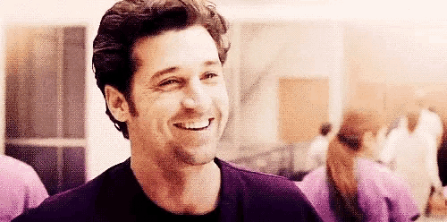 a man is smiling and looking at the camera while standing in front of a group of nurses .