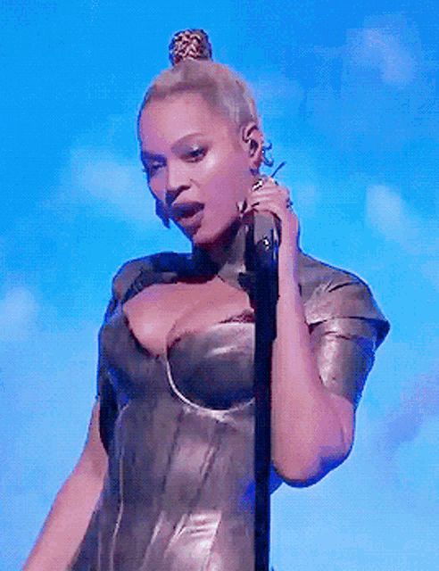 a woman singing into a microphone with a bun on her head