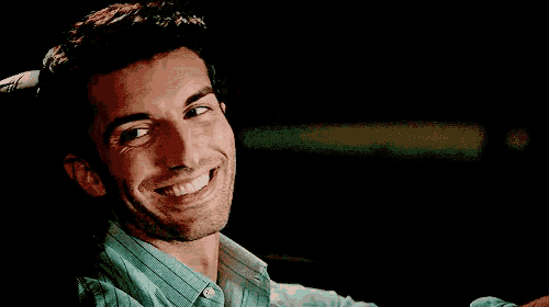 a man in a green shirt is smiling in a car .