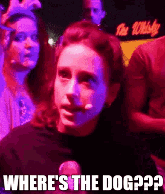 a woman is standing in front of a crowd of people in a dark room .
