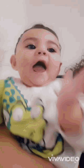a baby is being held by a person and making a funny face .
