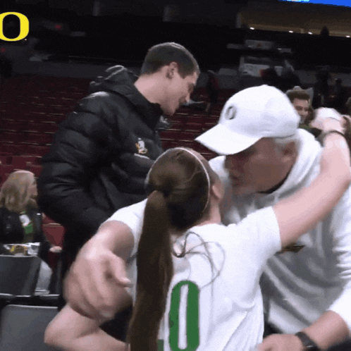 a man wearing a white hat with the letter o on it is hugging a girl wearing a white shirt with the number 10 on it