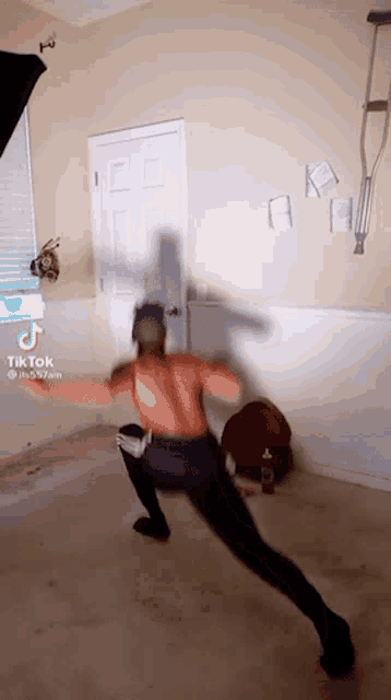 a man without a shirt is doing a karate pose in a room with a tiktok watermark