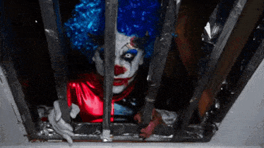 a clown in a blue wig behind bars