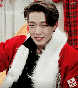 a young man is wearing a red jacket with a white fur trim