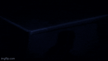 a person in a hoodie is standing in a dark room with blue lights on the ceiling ..