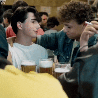 a group of young men are sitting at a table with glasses of beer