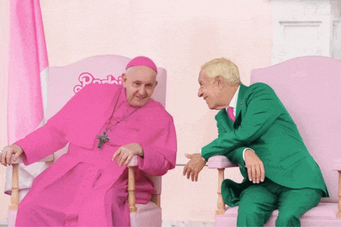 a man in a green suit sits next to a pink priest in a pink robe