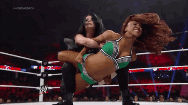 two women are wrestling in a ring with a w logo on the ring ropes