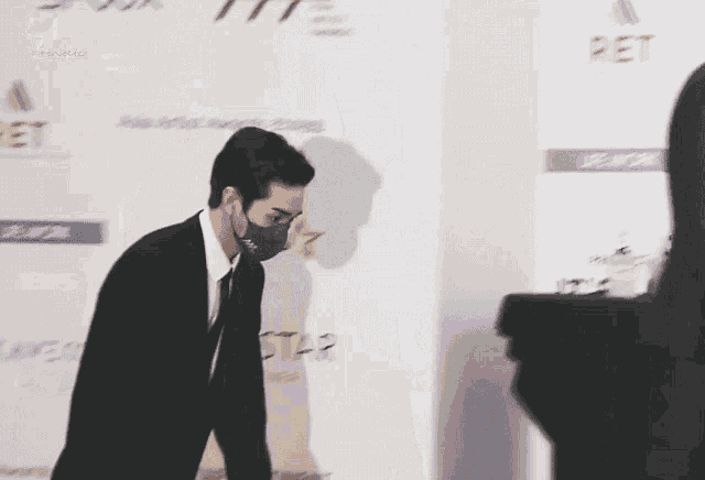 a man in a suit and tie stands in front of a wall that says pet