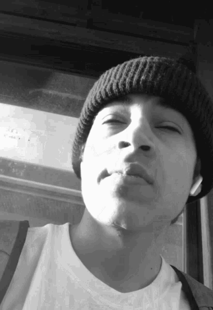 a man wearing a white shirt and a black beanie looks at the camera
