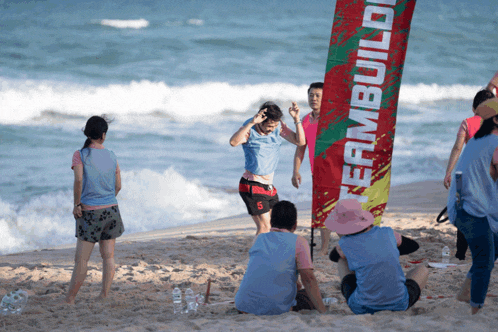 a group of people on a beach with a flag that says teambuild