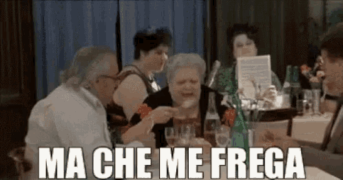 a group of people are sitting at a table in a restaurant with the words `` ma che me frega '' written on the bottom .