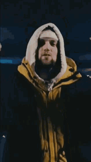 a man wearing a yellow and black jacket with a hood on his head